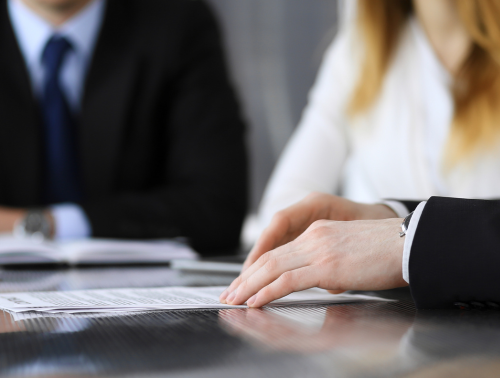 Three people sitting at a table, reviewing a document, representing Alternative Dispute Resolution (ADR) methods.