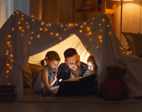 Image of a father reading a book to his children.