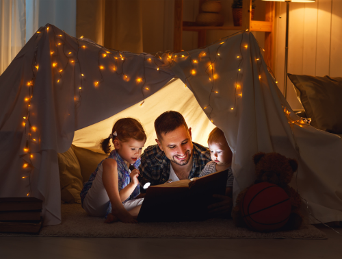Image of a father reading a book to his children.