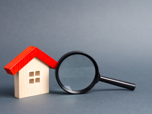Image of a wooden house and magnifying glass on a grey background, representing property searches.
