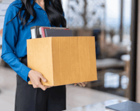 Woman holding box of items, implying unfair dismissal.