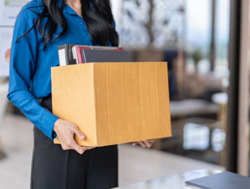 Woman holding box of items, implying unfair dismissal.