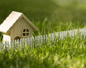 Image of a model house and a fence on grass, representing boundary disputes.