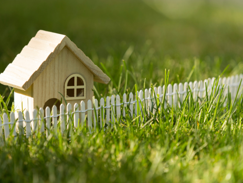 Image of a model house and a fence on grass, representing boundary disputes.