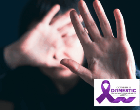 A person raising both hands toward the camera in a defensive gesture, representing domestic abuse.