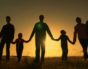 Silhouette of family holding hands at sunset, representing a blended family.